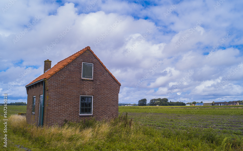 a small shed in a meadow field with a blue sky and clouds in the background. The Netherlands. a small shed in a meadow field with a blue sky and clouds in the background. The Netherlands.