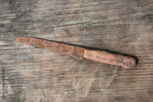 Ancient rusty knife on a wooden background