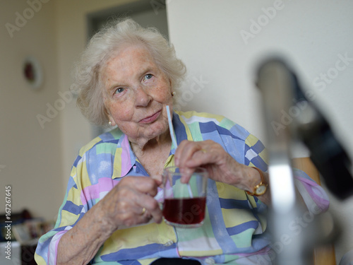 Eine an Parkinson-Demenz erkrankte ältere Patientin im Zimmer eines Pflegeheims. Krankheitsbedingt benötigt sie einen Strohhalm zum Trinken.