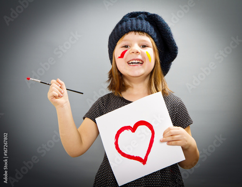 little painter girl with a drwan heart isolated on grey photo