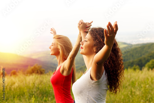 Portrait of two happy young woman on a viewpoint wit her arms outstretched.