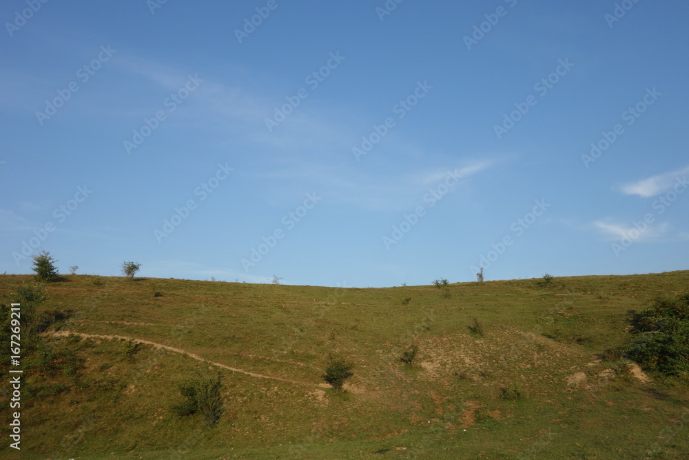 Green hill edge on blue sky