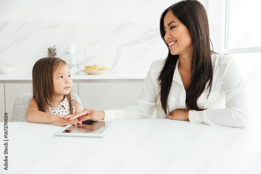 Happy mom sitting at the table with little cute girl Happy mom sitting at the table with little cute girl