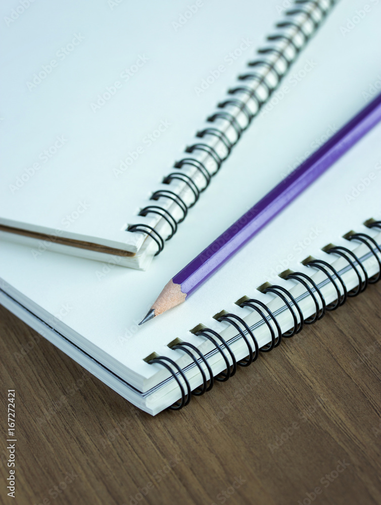Close up pencil and spiral notebook on wood table, Selective focus point Close up pencil and spiral notebook on wood table, Selective focus point