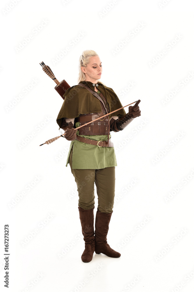 full length portrait of a blonde girl wearing green and brown medieval costume, holding a bow and arrow. isolated on white background. full length portrait of a blonde girl wearing green and brown medieval costume, holding a bow and arrow. isolated on white background.