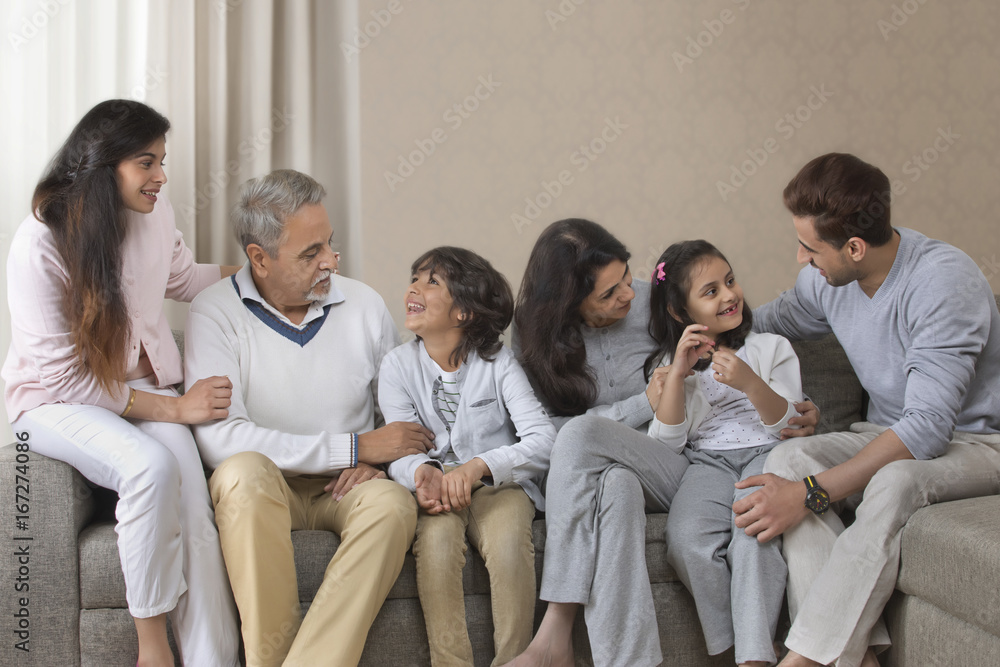 Happy multi-generation family sitting together on sofa Happy multi-generation family sitting together on sofa