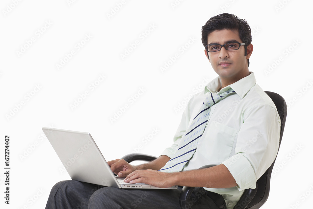 Confident young businessman on chair using laptop Confident young businessman on chair using laptop