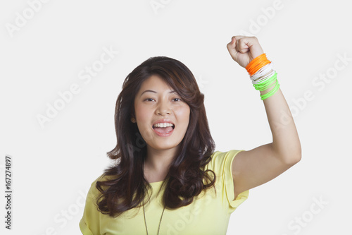 Portrait of beautiful young woman cheering with clenched fist over white background 