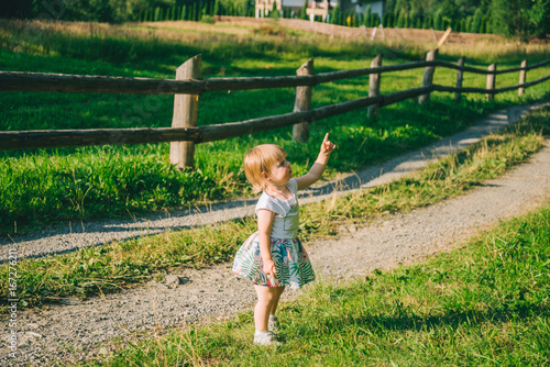 little girl stands on the country raod and point on somtheing photo