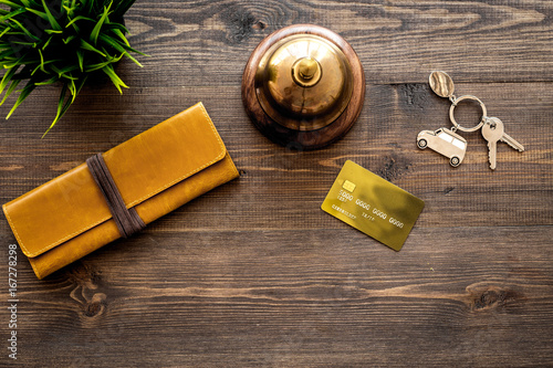 Pay for hotel room. Bank card near hotel service bell on dark wooden table top view copyspace