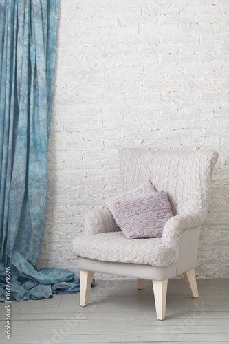 Classic soft armchair near brick wall