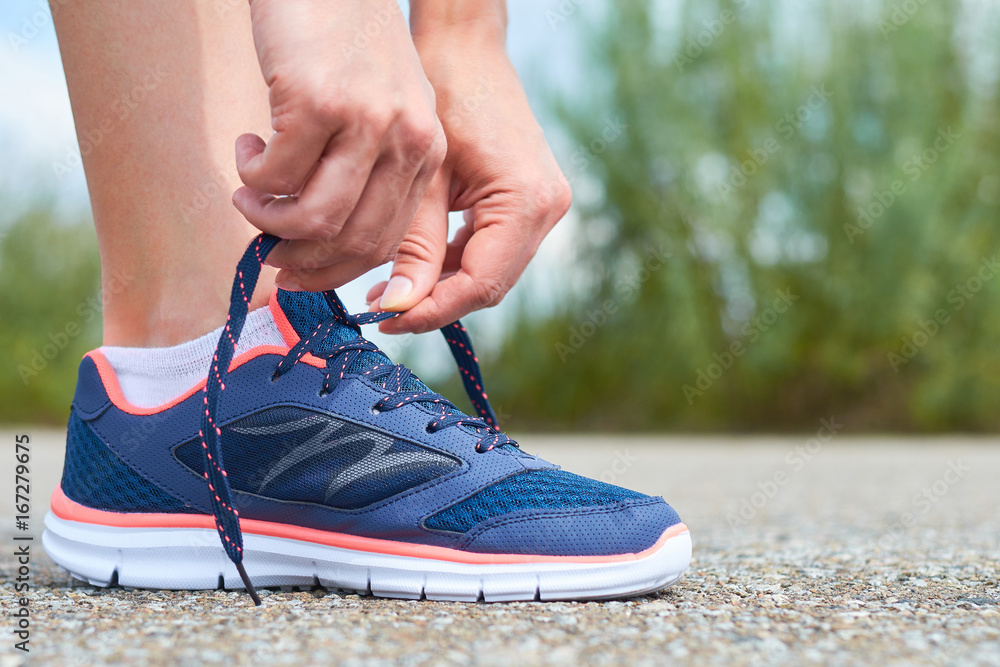 Girl ties up shoelaces in sneakers on road while jogging, legs and sneakers  Stock Photo | Adobe Stock