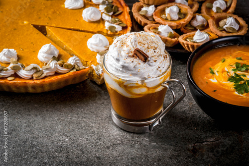 Set of traditional autumn food. Halloween, Thanksgiving. Spicy pumpkin latte, pumpkin pie and tartalets with whipped cream and pumpkin seeds, pumpkin soup, on black stone table. Copy space photo