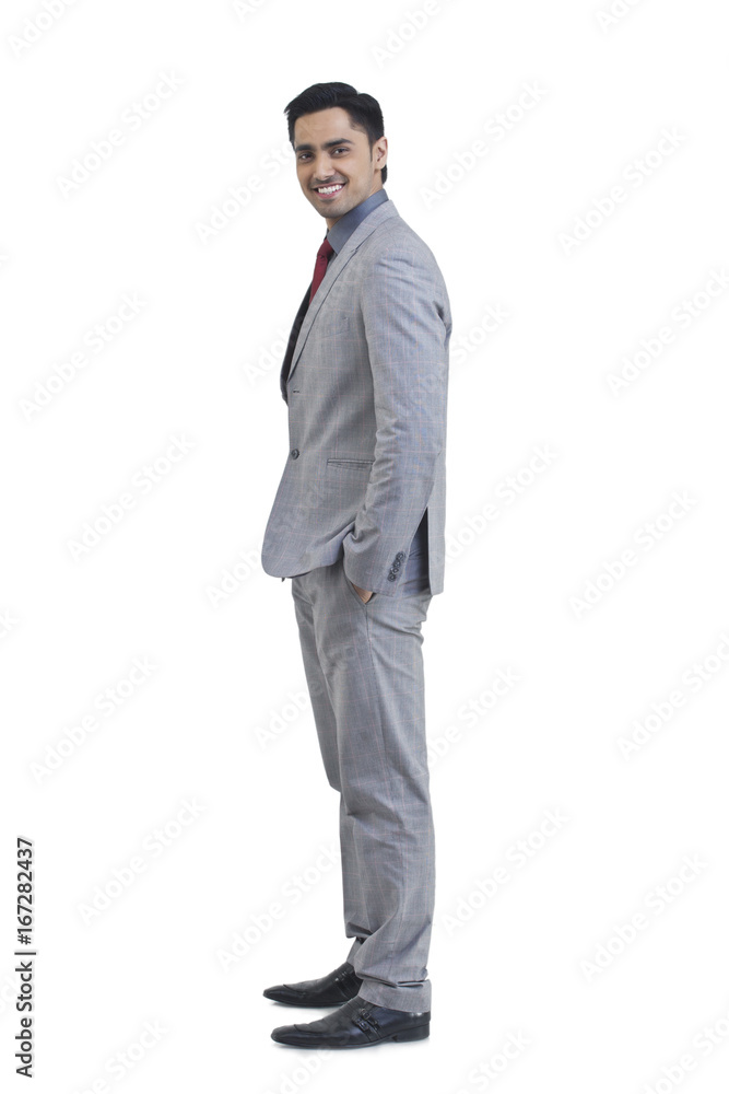 Side view of young businessman with hand in pocket standing against white background Side view of young businessman with hand in pocket standing against white background