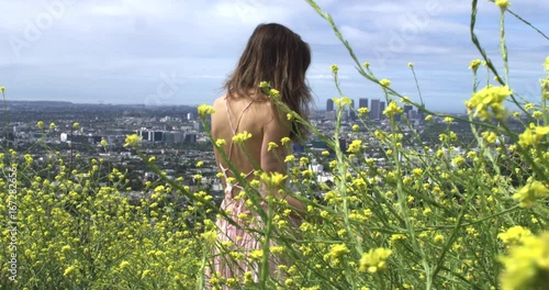 Follwing young woman in dress through budding flowers, slow motion photo