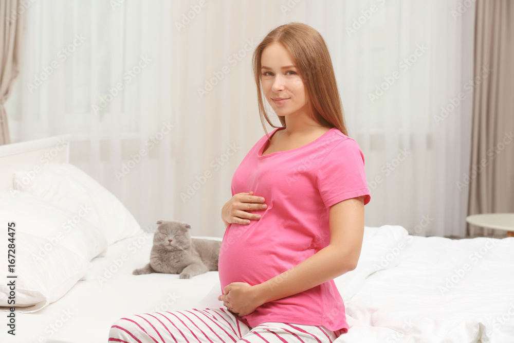 Young pregnant woman and cute cat on bed Young pregnant woman and cute cat on bed