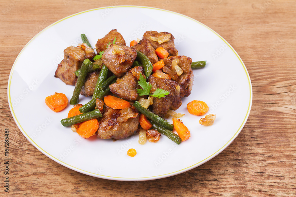 Sauteed liver with vegetables on white plate Sauteed liver with vegetables on white plate