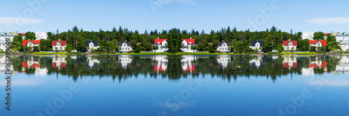 Typical summer view - cityscape of Reykjavik, capital of Iceland - lake shore with reflections in water.
