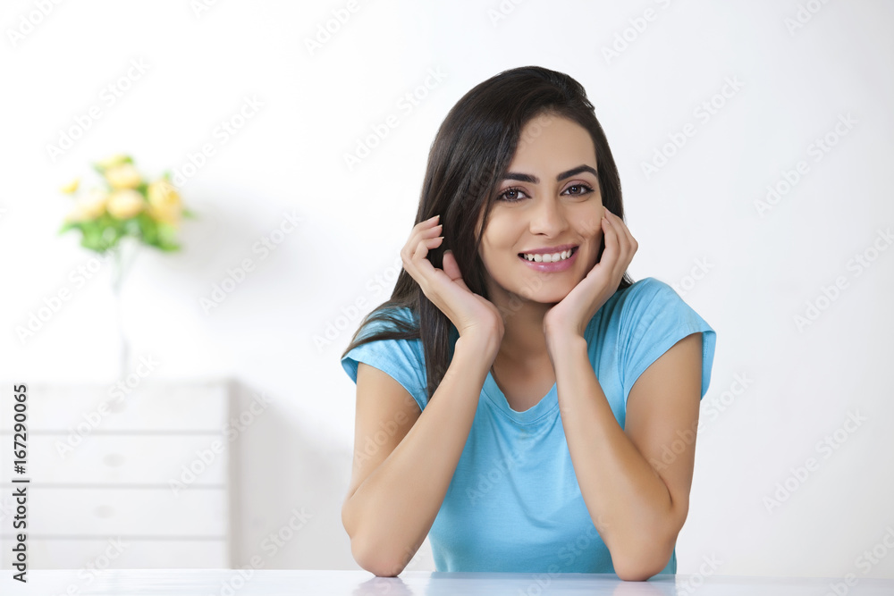 Portrait of beautiful young woman sitting at table in house Portrait of beautiful young woman sitting at table in house