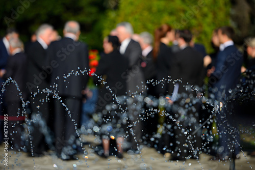 People in blur wearing black suits on funeral photo