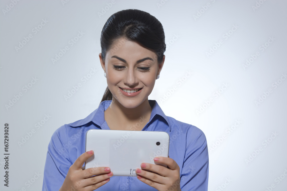 Smiling young businesswoman using digital tablet against gray background Smiling young businesswoman using digital tablet against gray background