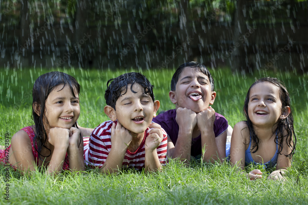 Little boys and girls lying on grass enjoying rain Little boys and girls lying on grass enjoying rain