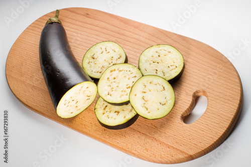 Partly sliced eggplant on a breadboard