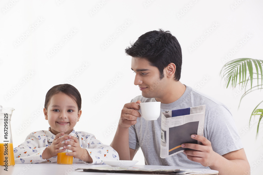 Father looking at daughter while having breakfast Father looking at daughter while having breakfast