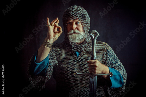 Powerful bearded knight with the sword on the dark background