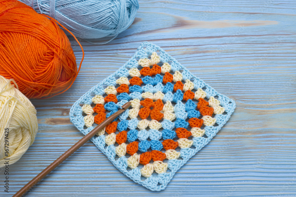 Crochet handmade granny square, a hook and yarn balls. The beginning of  bright plaid, blanket. Colorful original crochet handmade craft work.  Homemade creative craft. Photos | Adobe Stock