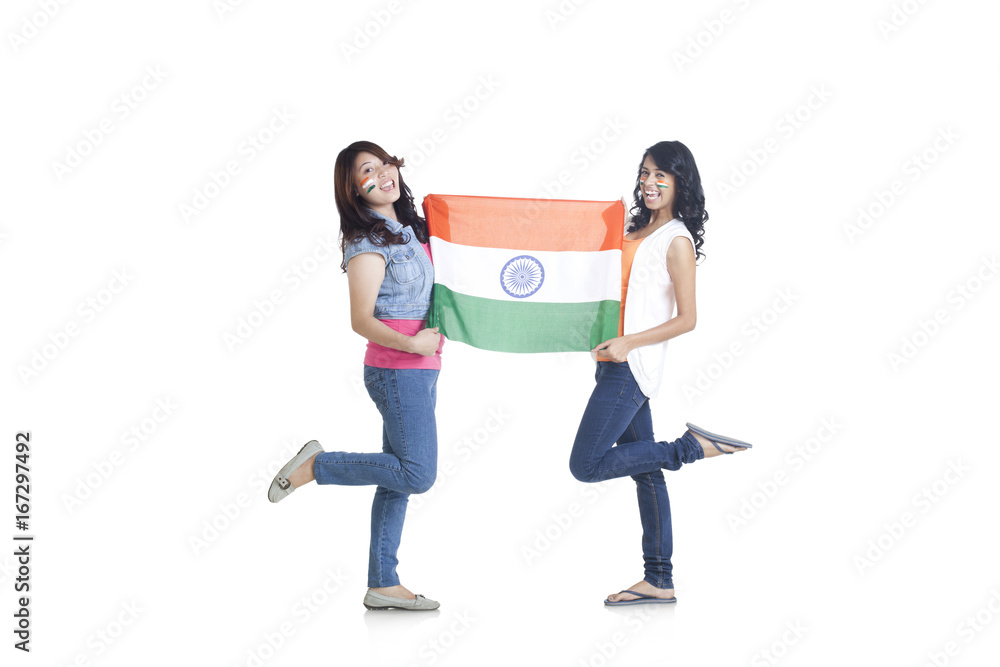 Fototapeta premium Full length portrait of young women in casuals holding Indian flag over white background 