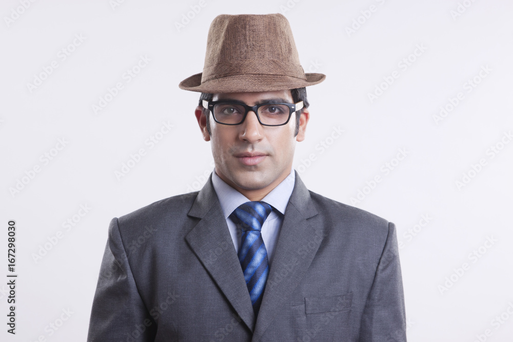 Portrait of confident businessman wearing hat and glasses against gray background Portrait of confident businessman wearing hat and glasses against gray background