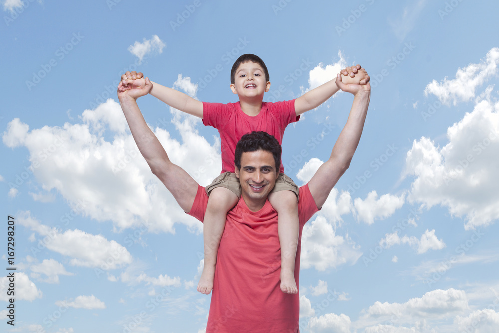 Portrait of happy father carrying son on shoulders against cloudy sky Portrait of happy father carrying son on shoulders against cloudy sky