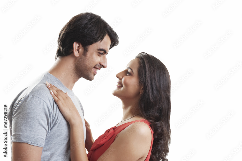Side view of loving couple looking at each other against white background