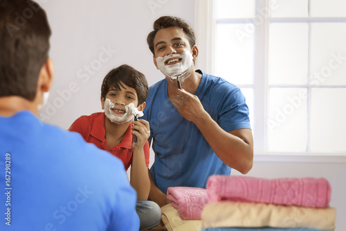 Fotografie Reflection of father and son shaving with razor in bathroom