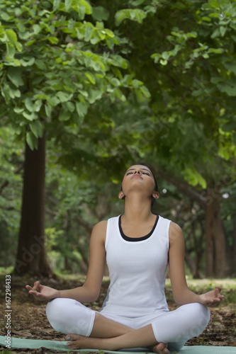 Young woman in lotus position meditating in a park 