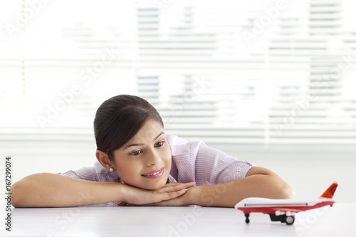 Thoughtful young business woman looking at airplane model 