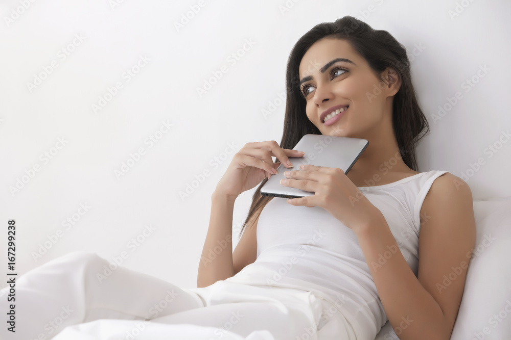 Thoughtful young woman with digital tablet in bedroom Thoughtful young woman with digital tablet in bedroom