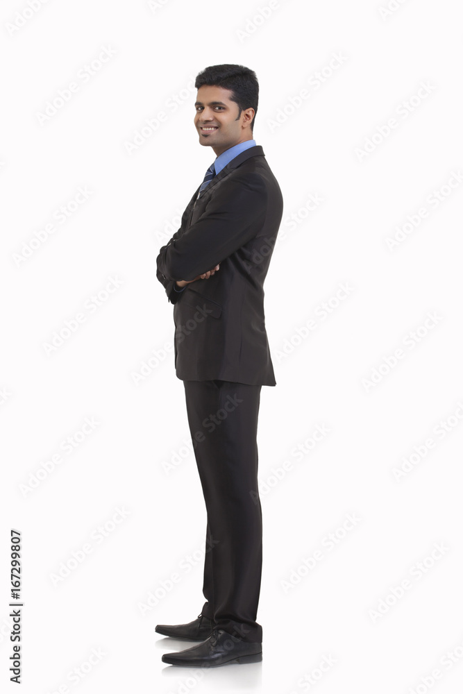 Side view of young businessman with arms crossed standing against white background Side view of young businessman with arms crossed standing against white background