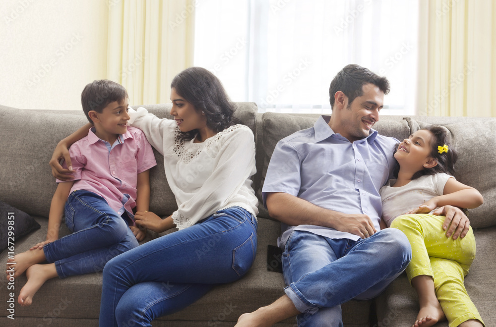 Mother hugging son and father hugging daughter relaxing on sofa Mother hugging son and father hugging daughter relaxing on sofa