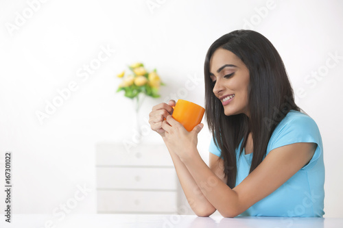 Beautiful young woman having coffee at home