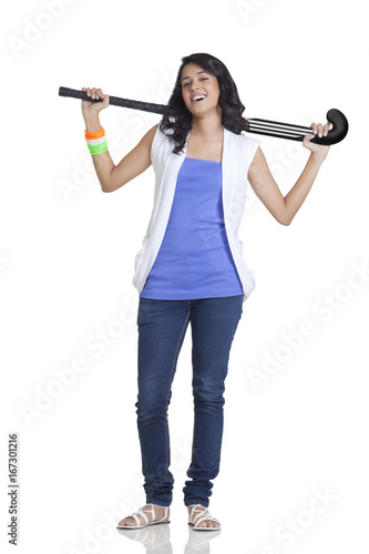 Full length portrait of young female holding hockey stick over white background 