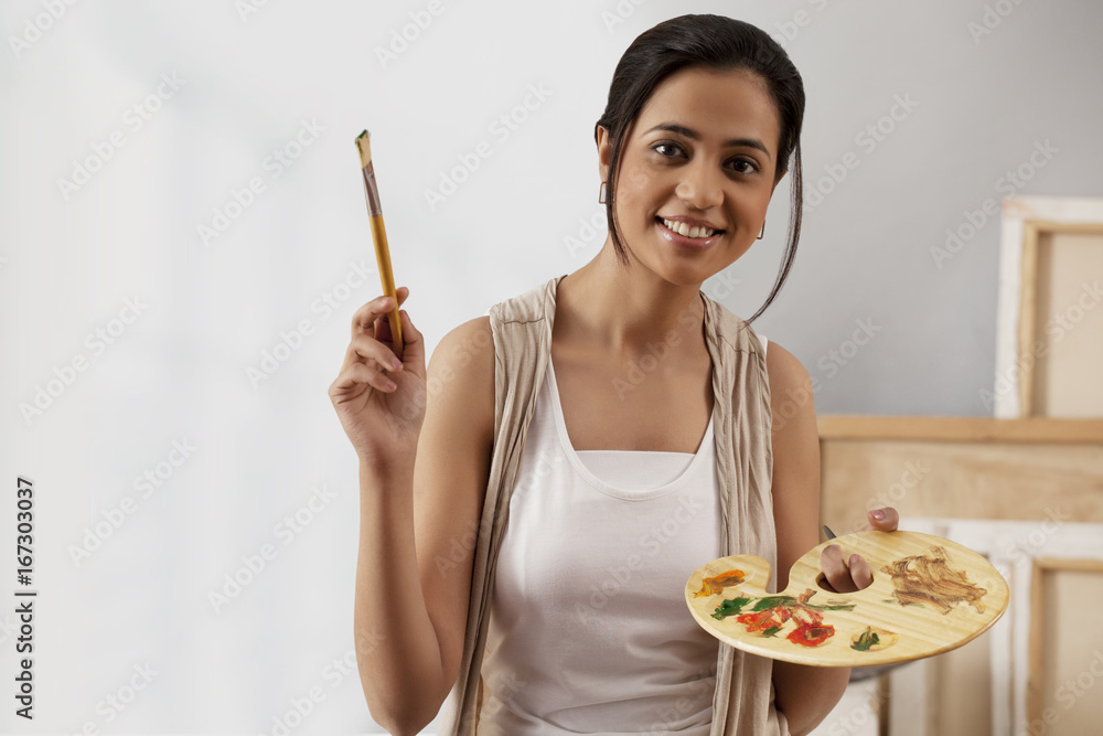 Portrait of young woman holding paintbrush and palette Portrait of young woman holding paintbrush and palette
