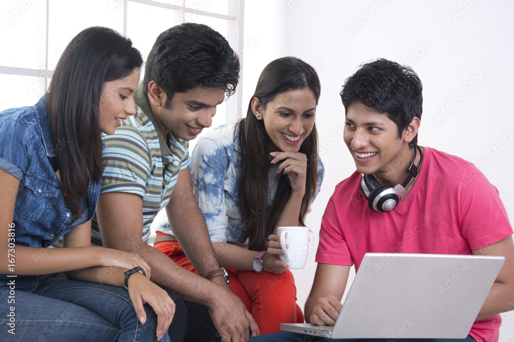 Happy friends using laptop in college Happy friends using laptop in college