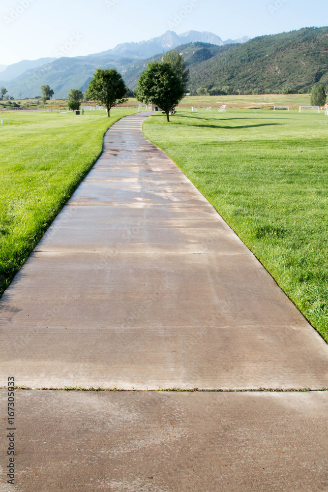 Wet concrete path with diminishing perspective towards the San Juan mountains in Colorado Wet concrete path with diminishing perspective towards the San Juan mountains in Colorado