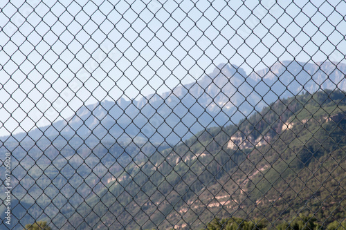 San Juan mountains through the repeating pattern of chain link fence