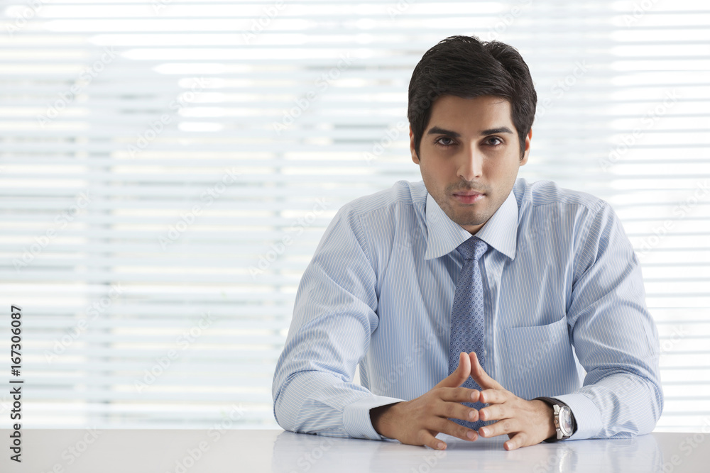 Portrait of handsome young businessman sitting in office Portrait of handsome young businessman sitting in office