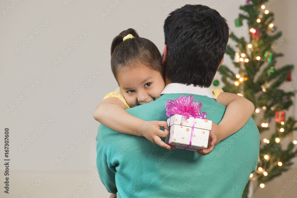 Girl hugs her dad while holding Christmas gift Girl hugs her dad while holding Christmas gift