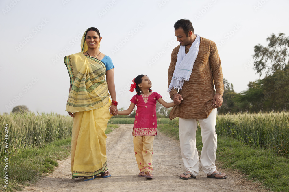Full length of an Indian family walking on a rural road Full length of an Indian family walking on a rural road