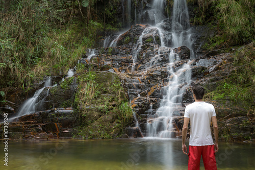 Man at waterfall. Beautiful waterfall in the forest. Natural water spring waterfall.